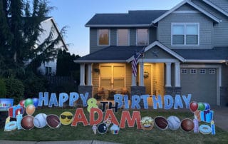 An Oregon City House with Happy Birthday yard card in Blue and a kid's sports theme