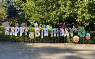Tye Dye Happy Birthday Letters decorate a hedge in Stafford Oregon