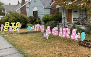Large Yard Card Letters in Pink and white that say It's a Girl in a front yard