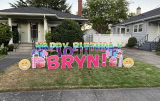 Rainbow colored yard greeting sign with colorful decorations in the front yard of a Portland home